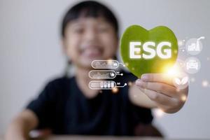 ESG text symbol on kid hands green leaf eco background, creative eco environment investment fund, future green energy innovation business trend.ESG of environmental Icon. photo