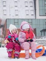 portrait of two little girls sitting together on sledges photo