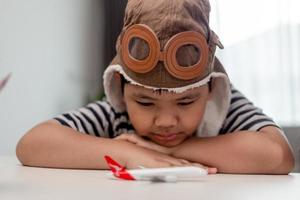 Little boy with wooden plane, boy wants to become pilot and astronaut. Happy child play with toy airplane. Kids pilot dreams of flying. Cute kids face. photo