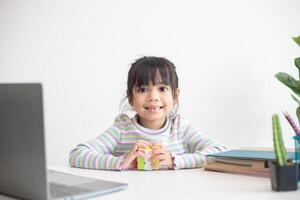 linda niña asiática sosteniendo el cubo de rubik en sus manos. el cubo de rubik es un juego que aumenta la inteligencia de los niños. foto