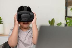 niño asiático con anteojos vr estudiando ciencias en casa, estudiante curioso usa un auricular de realidad virtual para estudiar ciencia en casa estudio en línea aprendizaje de estilo de vida futurista foto