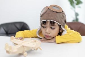 Asian little girl at home plays with a toy plane, she wants to become a pilot. Dreamer pilot. photo