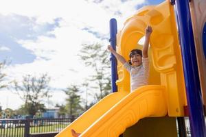 Little girl child going down the slide outdoors at the park or playground photo