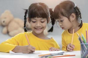 Two children draw a picture together on a sheet of paper at home photo