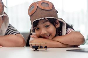 Asian little girl at home plays with a toy plane, she wants to become a pilot. Dreamer pilot. photo