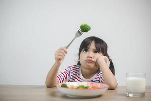 nutrición hábitos alimenticios saludables para el concepto de niños. A los niños no les gusta comer verduras. niña linda se niega a comer verduras saludables. foto