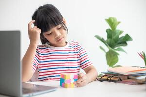 linda niña asiática sosteniendo el cubo de rubik en sus manos. el cubo de rubik es un juego que aumenta la inteligencia de los niños. foto