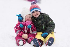 grupo de niños divirtiéndose y jugando juntos en la nieve fresca foto