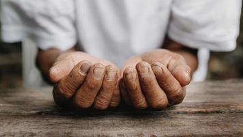 manos de un anciano en la mesa de madera. a la luz del sol foto