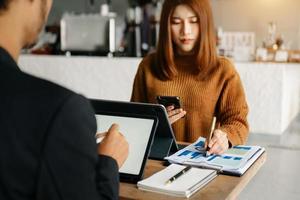 People using and looking at mockup laptop computer on wooden table together on office desk with clipping path tablet photo