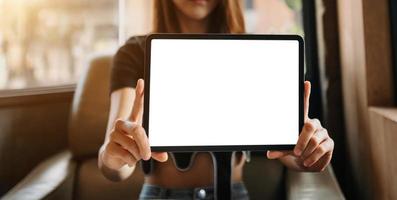 Mockup image of a beautiful woman holding and showing a tablet and smartphone with blank white screen while sitting at cafe photo