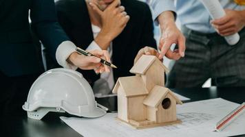 Close up shot of scale model house on table with architects. Two architects making architectural model in office together. to form a new buildin photo