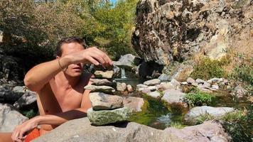 handsome young guy builds a cairn next to the river video