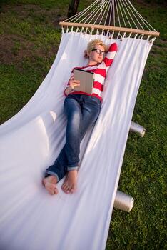 woman using a tablet computer while relaxing on hammock photo
