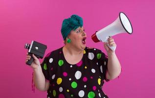 Funny plus size woman woman posing isolated on pink background studio portrait. People emotions lifestyle concept. Mock up copy space. Screaming in megaphone. photo