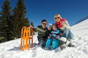 familia divirtiéndose en la nieve fresca en invierno foto