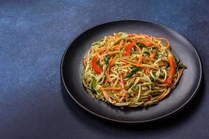 Fresh salad of sliced thin strips of carrot and zucchini on a concrete background photo