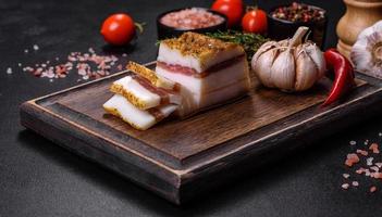 Smoked lard, bacon, half a piece, on a wooden dark cutting board photo