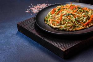 Fresh salad of sliced thin strips of carrot and zucchini on a concrete background photo