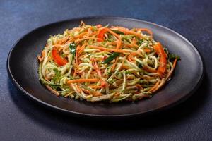 Fresh salad of sliced thin strips of carrot and zucchini on a concrete background photo