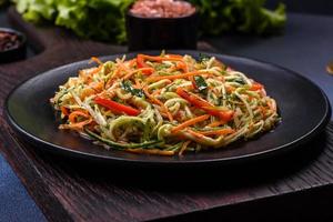 Fresh salad of sliced thin strips of carrot and zucchini on a concrete background photo