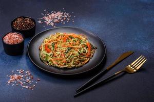 Fresh salad of sliced thin strips of carrot and zucchini on a concrete background photo