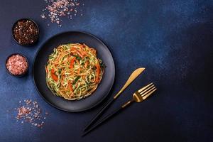 Fresh salad of sliced thin strips of carrot and zucchini on a concrete background photo