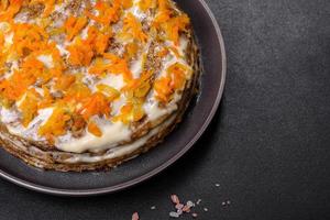 Delicious fresh liver cake with mayonnaise and carrots on a black plate against a dark concrete background photo