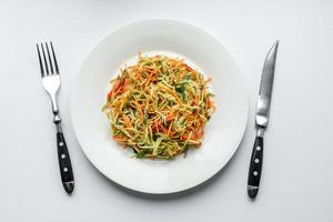 Fresh salad of sliced thin strips of carrot and zucchini on a concrete background photo