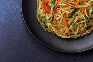 Fresh salad of sliced thin strips of carrot and zucchini on a concrete background photo