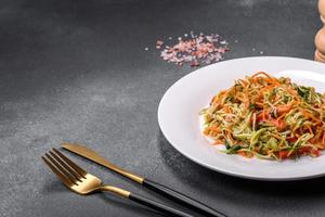 Fresh salad of sliced thin strips of carrot and zucchini on a concrete background photo