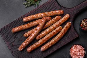 salchicha a la parrilla con la adición de hierbas y verduras en la tabla de cortar de madera foto