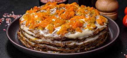 Delicious fresh liver cake with mayonnaise and carrots on a black plate against a dark concrete background photo