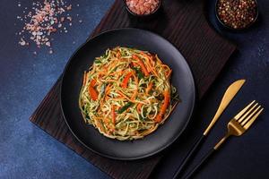 Fresh salad of sliced thin strips of carrot and zucchini on a concrete background photo