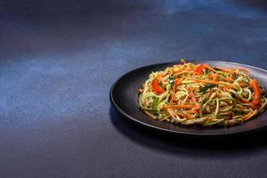 Fresh salad of sliced thin strips of carrot and zucchini on a concrete background photo