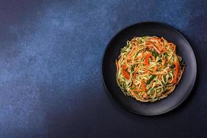 Fresh salad of sliced thin strips of carrot and zucchini on a concrete background photo