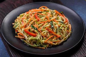 Fresh salad of sliced thin strips of carrot and zucchini on a concrete background photo