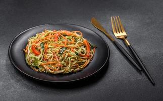 Fresh salad of sliced thin strips of carrot and zucchini on a concrete background photo