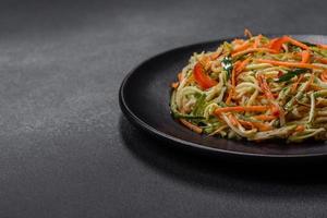 Fresh salad of sliced thin strips of carrot and zucchini on a concrete background photo