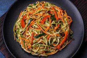 Fresh salad of sliced thin strips of carrot and zucchini on a concrete background photo