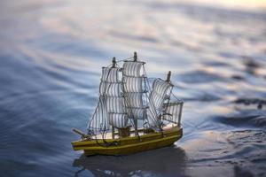 un barco decorativo de juguete al atardecer en el agua en el mar por la noche. foto