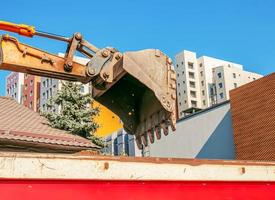 trabajos de excavación. el cubo del tractor carga el suelo con una pala en la parte trasera de un camión volquete en el sitio de construcción. foto