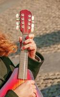 A young man plays the mandolin in the city on the street. Close-up hands photo