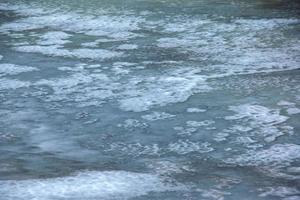 fondo invernal de la superficie helada del río. textura de hielo cubierto de nieve. foto