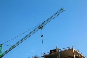 grúa de construcción contra el cielo azul. la industria de bienes raices una grúa utiliza equipos de elevación en un sitio de construcción. foto