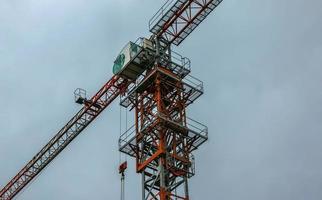 Construction crane against the blue sky. The real estate industry. A crane uses lifting equipment at a construction site. photo