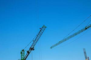 grúa de construcción contra el cielo azul. la industria de bienes raices una grúa utiliza equipos de elevación en un sitio de construcción. foto