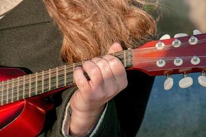 A young man plays the mandolin in the city on the street. Close-up hands photo