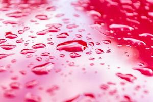 Drops of water on a red metal surface. photo