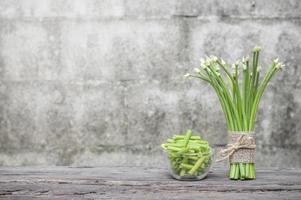 Chives flower or Chinese chives on wooden table and chives slice in glass bowl with old brick wall background photo